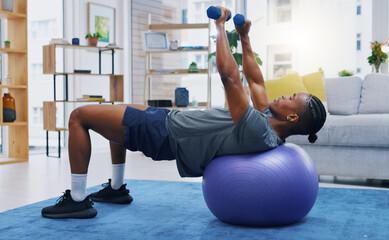 Fototapeta na wymiar Fitness, home workout and a black man lifting weights on an exercise ball for strong muscles in the living room. Gym, health and a male athlete training in a house for wellness, strength or lifestyle