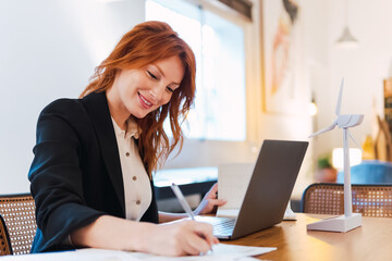 Cheerful young businesswoman sitting at her workplace