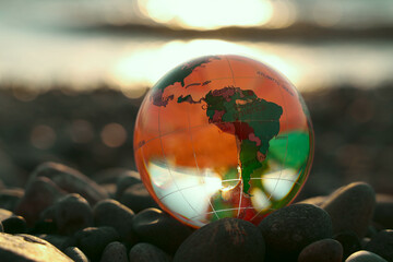 glass globe ball on pebble beach background. Crystal Ball on the beach of the Black sea. sunset...