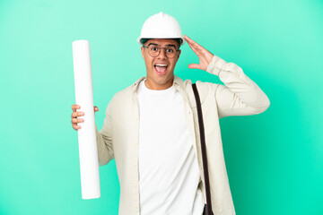 Young architect man holding blueprints over isolated background with surprise expression