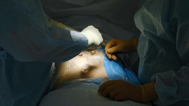 The doctor makes an incision with a scalpel on the abdomen. Plastic surgery operation. 