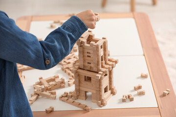 Fototapeta Little boy playing with wooden tower at table indoors, closeup. Child's toy obraz