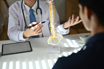 Obraz premium Experienced male orthopedist giving consultation about scoliosis or spinal problems during medical exam
