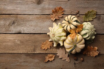Fresh ripe pumpkins and dry leaves on wooden table, flat lay. Space for text