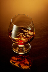 Close up top view of glass of whiskey, rum, brandy or bourbon over golden gradient background.