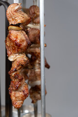 Cooking pork meat in an electric kebab maker on vertical skewers