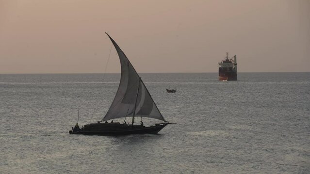 traditional commercial sailing dhow on the ocean water entering leaving harbour port heading for destinations