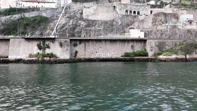 Muralha Fernandina old walls seen from moving boat over Douro River, Porto