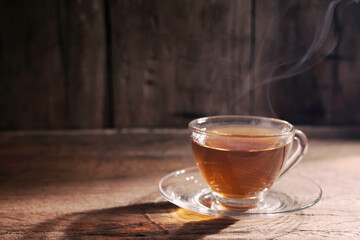 hot tea into a teacup. A cup of herbal tea placed on an old wooden table, dark background. A day...