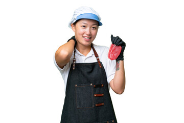 Young caucasian woman wearing an apron and serving fresh cut meat over isolated background laughing