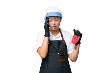 Young caucasian woman wearing an apron and serving fresh cut meat over isolated background with headache
