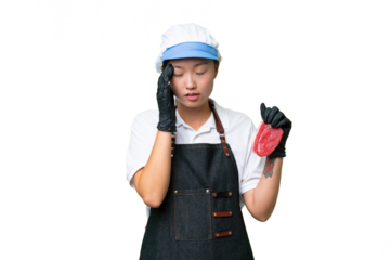 Young caucasian woman wearing an apron and serving fresh cut meat over isolated background with headache
