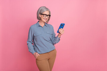 Photo of lovely positive pensioner lady wear trendy clothes hold use iphone samsung stand empty...