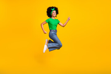 Fototapeta na wymiar Full length profile portrait of delighted carefree girl jump raise fist success achievement isolated on yellow color background