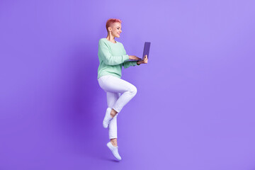 Full length photo of cute cheerful lady dressed teal pullover jumping communicating modern gadget isolated purple color background