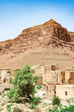 Mudbrick buildings of an ancient village with red canyons in backgrounds, Ziz Valley, Atlas mountains, Morocco
