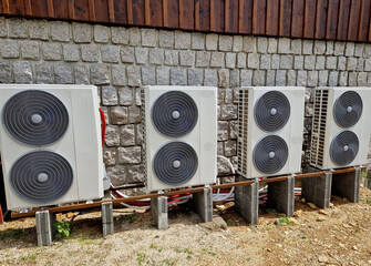 Cooling units in a row in the backyard of a cabin in the mountains. stone block wall and wooden...