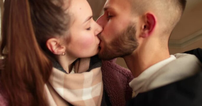 A young couple in love say goodbye with passionate kisses and hugs after a romantic date in the hallway of an apartment building.