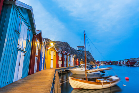 Colorful fishing huts with wooden boat moored at the jetty at dusk, Smogen, Bohuslan, Vastra Gotaland, West Sweden, Sweden, Scandinavia