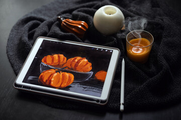 The still life picture with pumpkins drawn on the electronic tablet next to extinguished candle and ceramic pumpkin figurine on black table. Halloween, Thanksgiving day