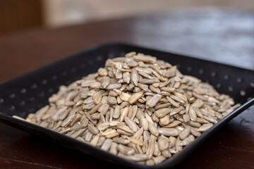 Pile of peeled sunflower seeds on black plate.