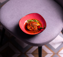 grilled chicken thigh on orange plate red hot chili pepper