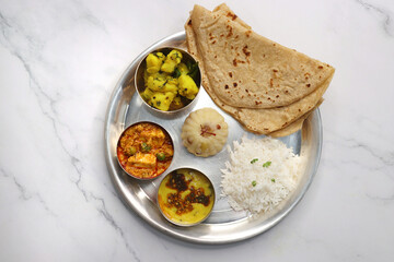 Indian vegetarian Thali or platter includes Aloo ki sabji, dal rice, Roti bhaji, Matar Paneer, Sheera or suji ka halwa, chapati. Indian food is served in a Silverplate or thali. Copy Space. Veg Thali