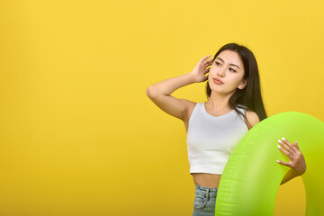 Confident young girl holds an inflatable circle of bright color in her hand, straightens her hair...