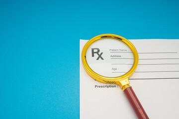 Top view of a magnifying glass over the medical prescription sheet on a blue background