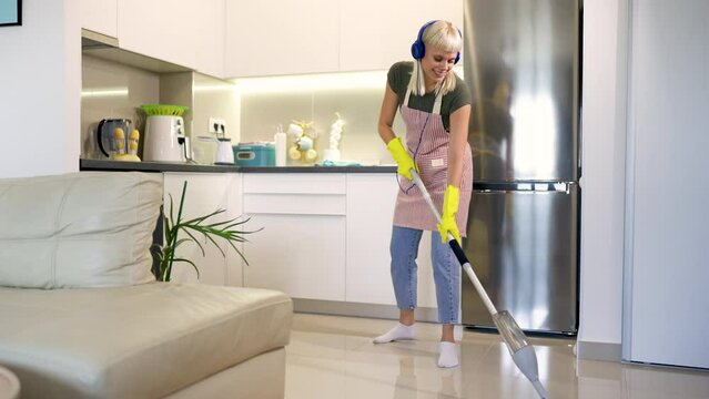 Young blonde woman cleaning a kitchen floor