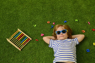 Hebrew alphabet. The boy lies on the grass, letters lie around his head. Concept: education in...