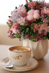 Coffee cup cappuccino and a bouquet of flowers. Hygge lifestyle, cozy mood.