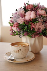 Coffee cup cappuccino and a bouquet of flowers. Hygge lifestyle, cozy mood.