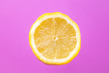 Lemon slice floating in front of pink background 