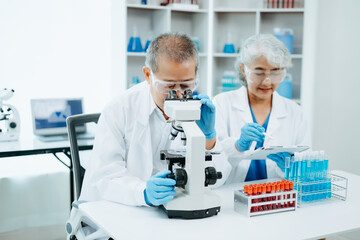 Fototapeta premium Two scientist or medical technician working, having a medical discuss meeting with Asian senior female scientist supervisor in the laboratory with online reading, test samples and innovation
