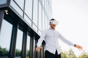 Businessman wearing virtual reality glasses standing outdoors and peering at the camera