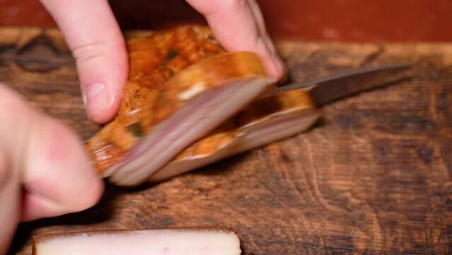Slicing of salted pork fatback on cutting board, close-up. Ukrainian traditional food - salo