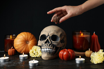 Skull, pumpkins, candles and hand on black background