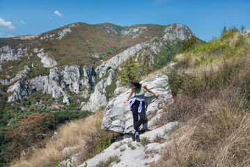Naklejka na ściany i meble Woman standing in the summer mountain with stunning view 