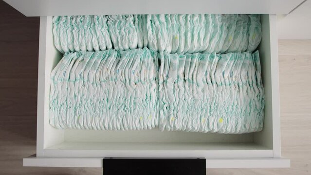 opening of a chest of drawers with baby diapers that absorb moisture, protection against leakage. Hygiene for children, close-up