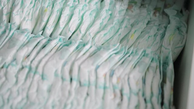 White dresser drawer full of baby diapers. Hygiene products against liquid leakage for children. Humidity indicator, cotton, close-up