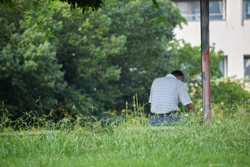 夏の公園のベンチで休憩しているシニア男性の後姿