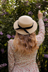  A young girl in a straw hat stands with her back to the flowering trees.