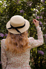  A young girl in a straw hat stands with her back to the flowering trees.