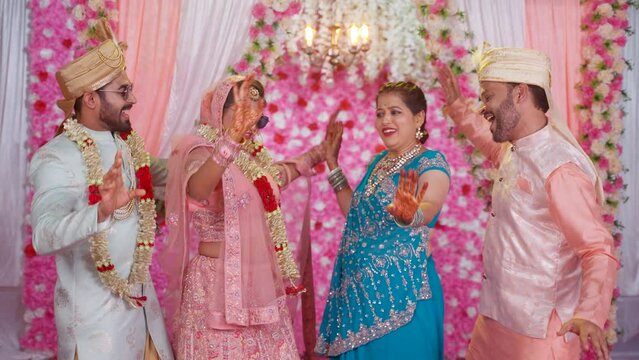 Happy Indian Family dancing at Wedding - Excited Middle aged parents with Bride and groom dancing together at marriage - concept of family gathering, joyful moments and special occasion.