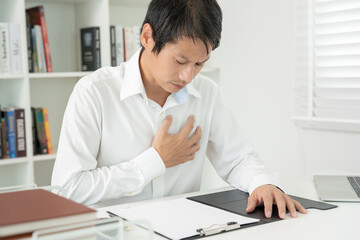 hand hold chest with heart attack symptoms, asian man working hard have chest pain caused by heart disease, leak, dilatation, enlarged coronary heart, press on the chest with a painful expression