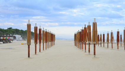 Prospettiva sulla spiaggia autunnale con gli ultimi ombrelloni piantati nella sabbia