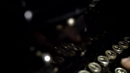 fingers typing on a typewriter in dark room