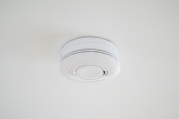 Simple plain fire alarm detector on the white ceiling