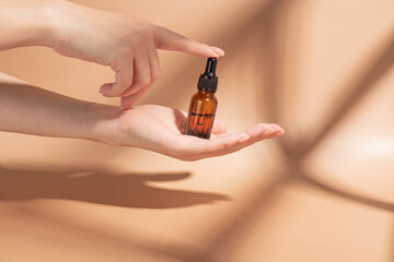 Hand, product and serum with a woman on a beige background to promote an antiaging treatment....